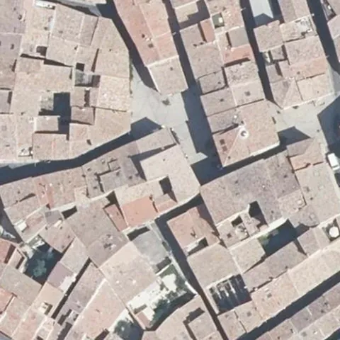 Quatre-vingt-dix mètres de toits d'un centre ancien vus du ciel, les contours des bâtiments au trait blanc, l'immeuble désigné en vert